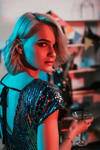 Atractiva chica rubia sosteniendo vaso con cóctel en la fiesta - foto de stock