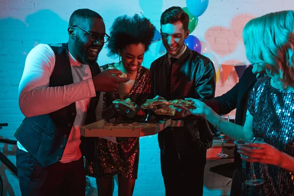 Jovens homens e mulheres comendo pizza e segurando bebidas na festa — Fotografia de Stock