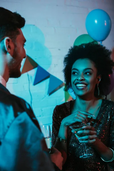 Casal feliz segurando óculos e falando na festa — Fotografia de Stock