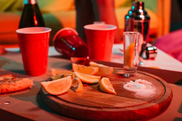 Copos de plástico com bebidas e laranjas fatiadas na mesa de festa — Fotografia de Stock