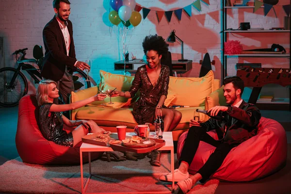 Young men and women toasting with champagne in decorated room — Stock Photo