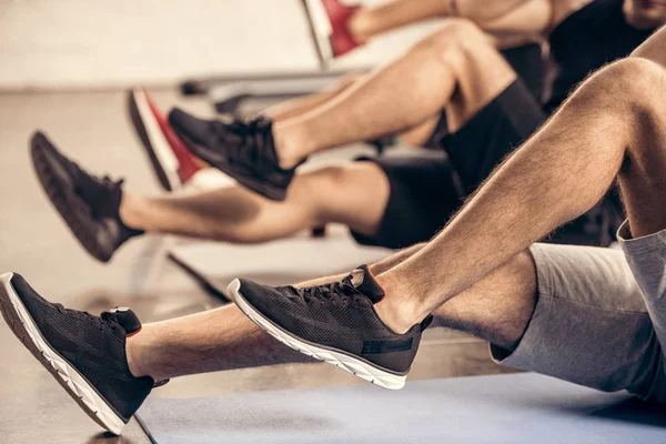 Imagem cortada de desportistas fazendo sit ups juntos no ginásio — Fotografia de Stock