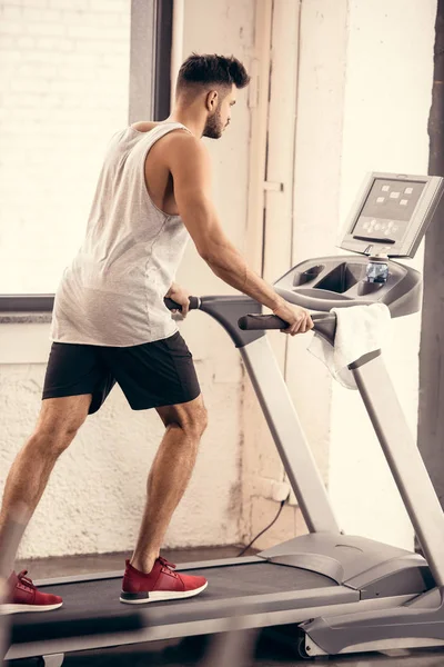 Vue latérale du beau sportif marchant sur tapis roulant dans la salle de gym — Photo de stock