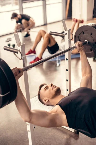 Bonito desportista levantamento barbell no ginásio — Fotografia de Stock