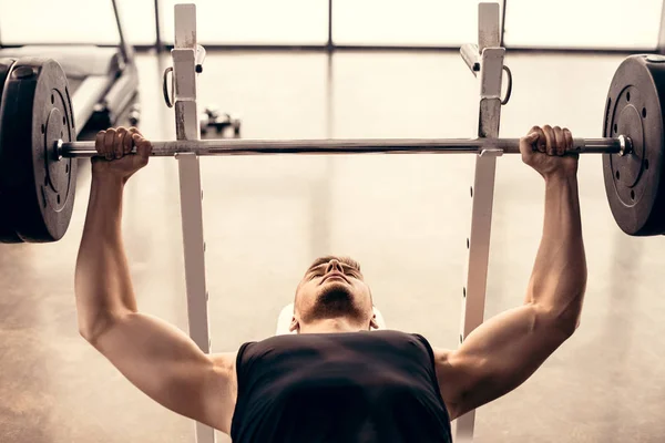 Beau sportif musclé levant haltère dans la salle de gym — Photo de stock