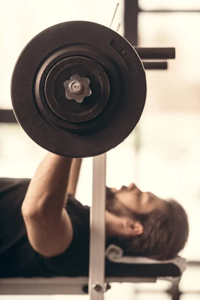 Side view of handsome sportsman lifting barbell with weights in gym — Stock Photo