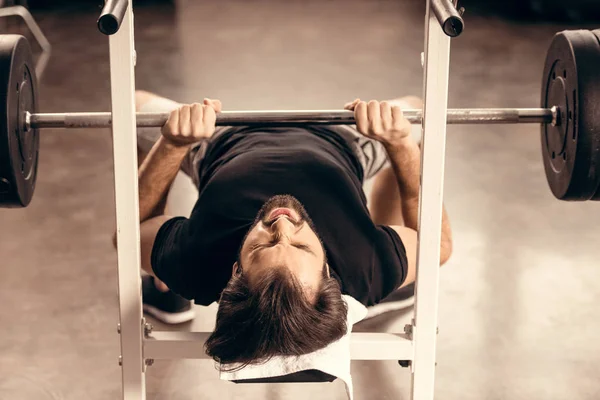 Schöner Sportler, der im Fitnessstudio auf Bankdrücken trainiert — Stockfoto