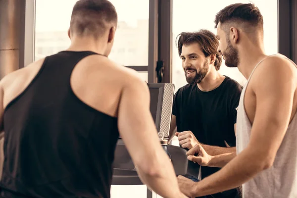 Lächelnde gutaussehende Sportler in der Nähe von Laufband in der Turnhalle — Stockfoto