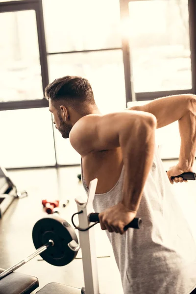 Vista lateral de deportista guapo haciendo pull ups en el gimnasio - foto de stock