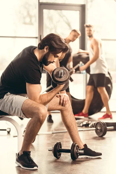 Vista laterale del bellissimo allenamento muscolare uomo con manubri in palestra — Stock Photo