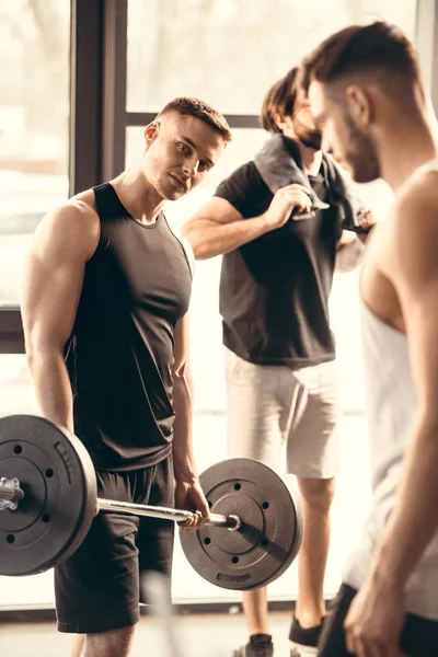 Musclé beaux jeunes hommes exerçant ensemble dans la salle de gym — Photo de stock