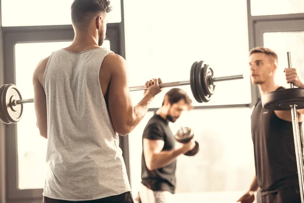 Giovani sportivi che si allenano con i bilancieri nel centro sportivo — Foto stock