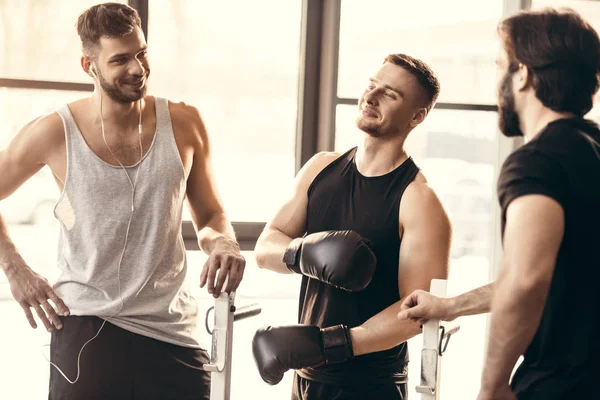 Three sporty young men on sportswear talking in gym — Stock Photo