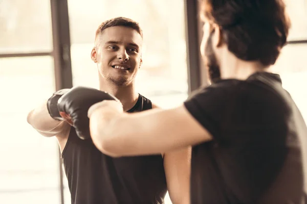 Selective focus of young athletes in boxing gloves greeting each other in gym — Stock Photo
