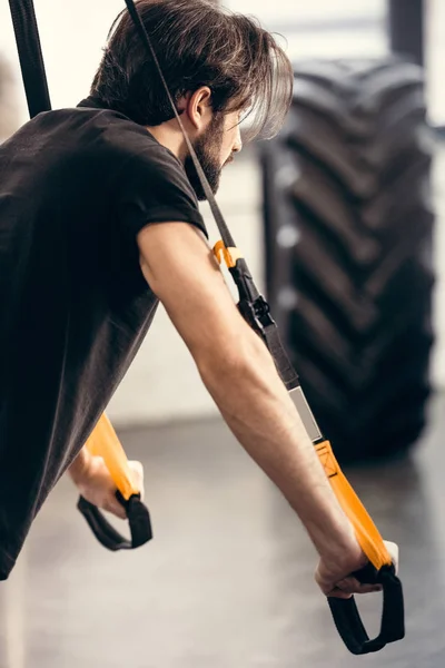 Вид збоку спортивного молодого чоловіка тренування з фітнес-ремінцями в спортзалі — стокове фото