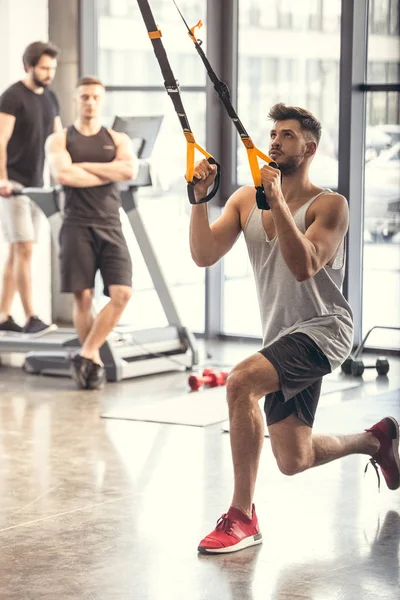 Athletic young man training with resistance bands in sports center — Stock Photo