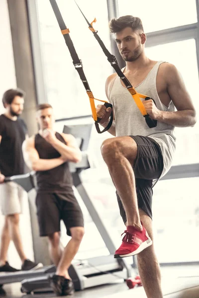 Schöner sportlicher junger Mann beim Training mit Federbeinen im Fitnessstudio — Stockfoto