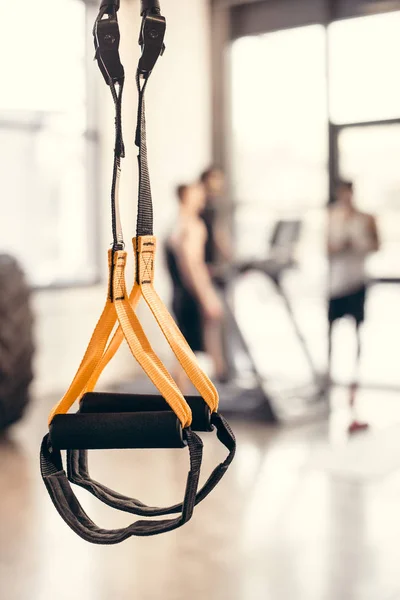 Vista de cerca de correas de fitness y jóvenes deportistas de pie en el gimnasio - foto de stock