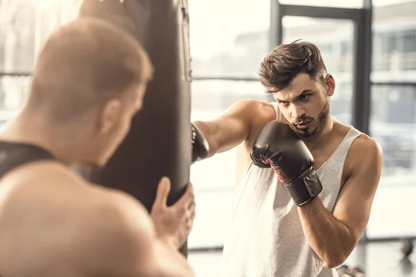 Selective focus of sportsmen training with punching bag in gym — Stock Photo
