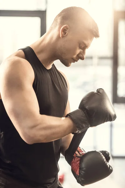 Side view of muscular young sportsman wearing boxing gloves — Stock Photo