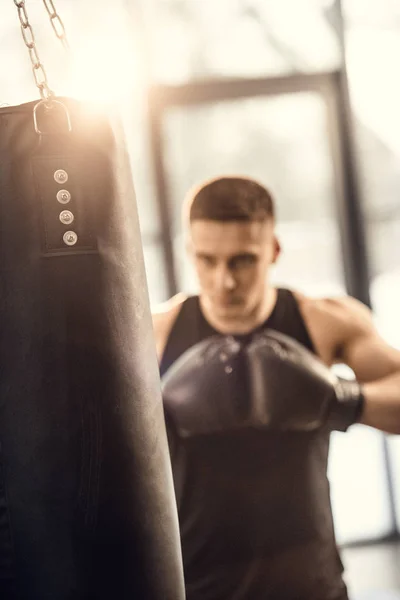 Messa a fuoco selettiva di atletico giovane pugilato con sacco da boxe — Foto stock