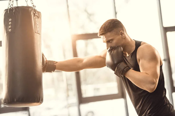 Entraînement musclé jeune boxeur avec sac de boxe dans la salle de gym — Photo de stock