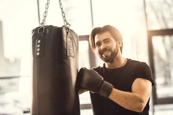 Schöner junger Mann boxt und lächelt in Turnhalle in die Kamera — Stockfoto