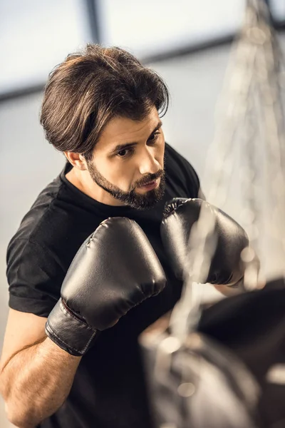 Vista ad alto angolo del bel giovanotto in guanti da boxe allenamento in palestra — Foto stock