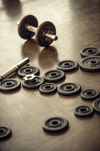 Dumbbell, iron bar and weight plates in gym — Stock Photo