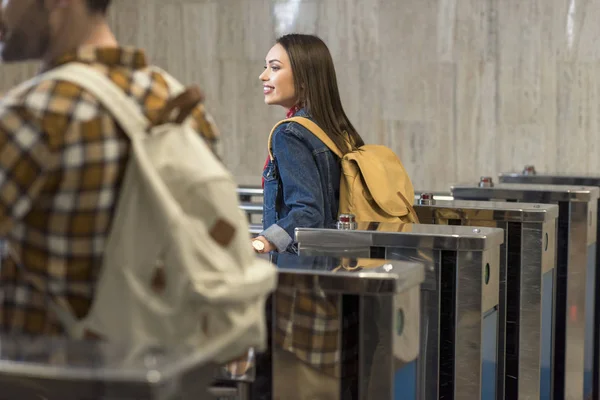 Stylish tourists with backpacks passing through turnstiles — Stock Photo