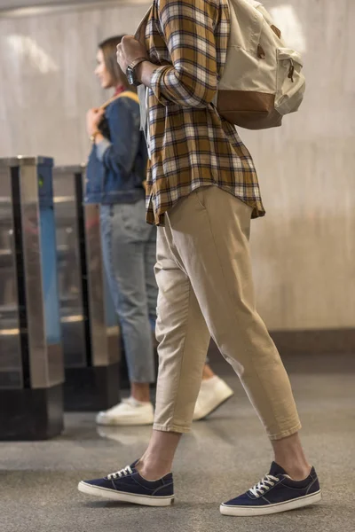Cropped shot of stylish tourists with backpacks passing through turnstiles — Stock Photo
