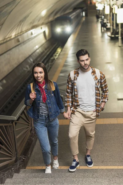 Couple of stylish tourists with backpacks at subway station — Stock Photo