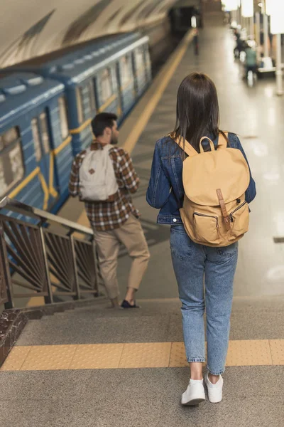 Вид ззаду стильних мандрівників з рюкзаками, що йдуть вниз на станції метро — стокове фото