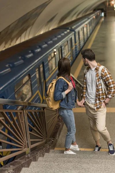 Voyageurs élégants avec des sacs à dos debout sur les escaliers à la station de métro — Photo de stock