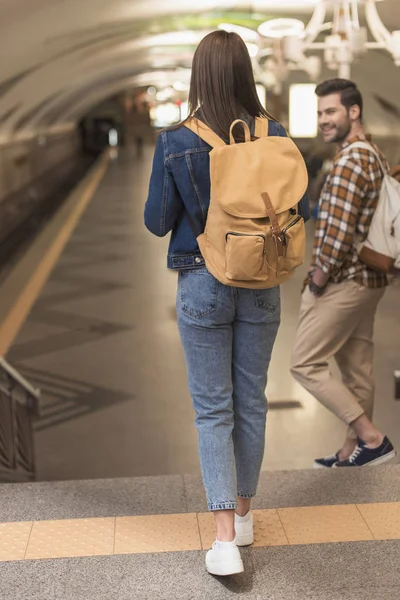 Stylish travelers with backpacks going downstairs at subway station — Stock Photo