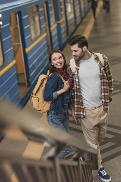 Sonriente turista femenina con novio en la estación de metro - foto de stock