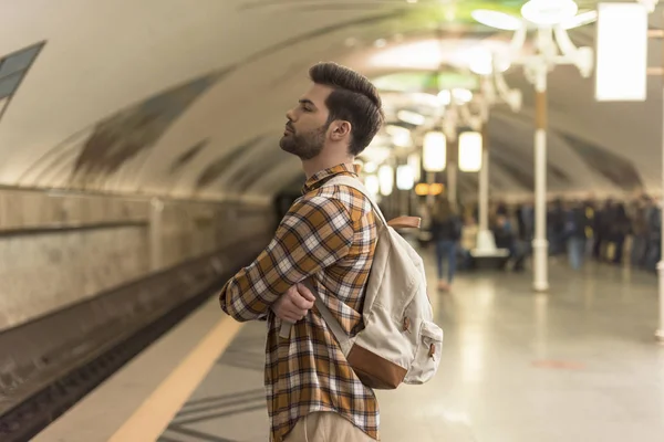 Vista lateral del hombre con estilo con los ojos cerrados esperando tren en la estación de metro - foto de stock