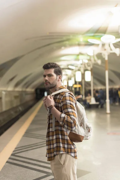 Молодий чоловік з рюкзаком чекає потяг на станції метро — стокове фото