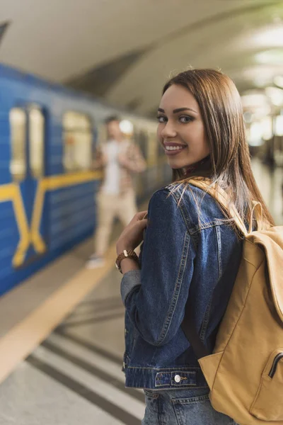 Усміхнена стильна жінка-туристка з рюкзаком на станції метро — стокове фото