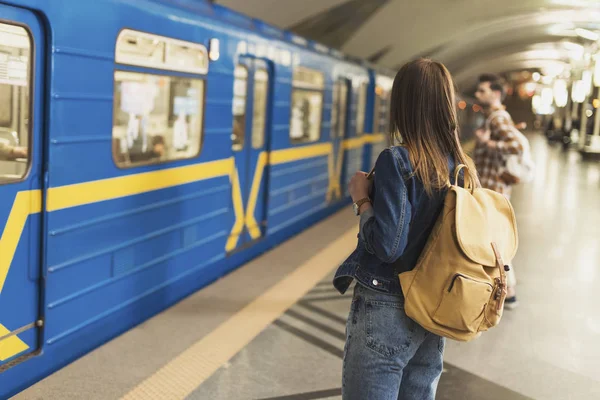 Вид сзади стильной туристки с рюкзаком, стоящим на станции метро — стоковое фото