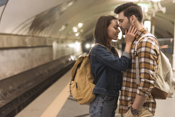 Vista lateral del viajero femenino abrazando novio en la estación de metro - foto de stock