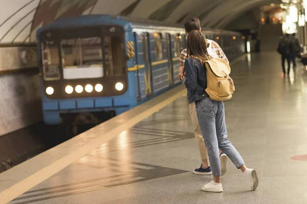 Rear view of stylish couple of travelers with backpacks at metro station — Stock Photo