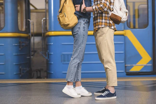 Cropped image of stylish couple of tourists embracing each other at subway station — Stock Photo