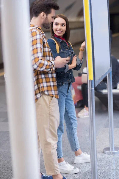 Side view of stylish tourists looking at information board at metro station — Stock Photo