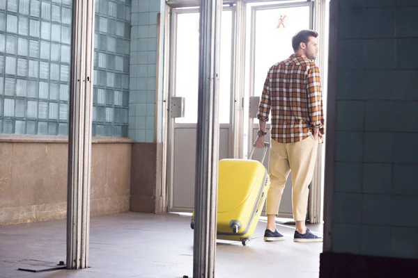 Rear view of male tourist with wheeled bag at subway exit — Stock Photo