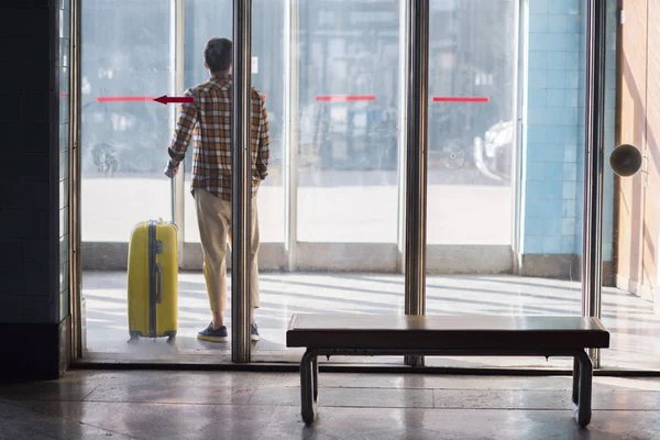 Rear view of stylish male tourist with wheeled bag at subway station — Stock Photo