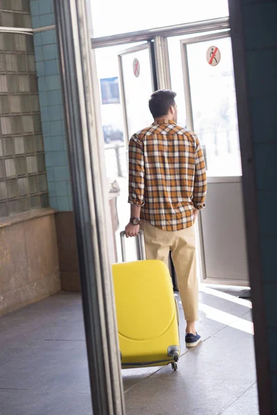 Rear view of stylish male tourist with wheeled bag at subway exit — Stock Photo