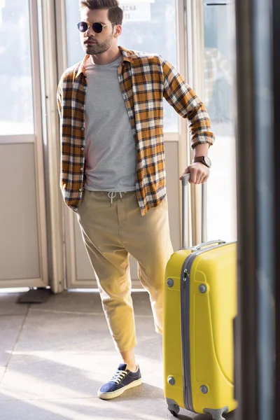 Stylish male tourist in sunglasses with wheeled bag at subway exit — Stock Photo