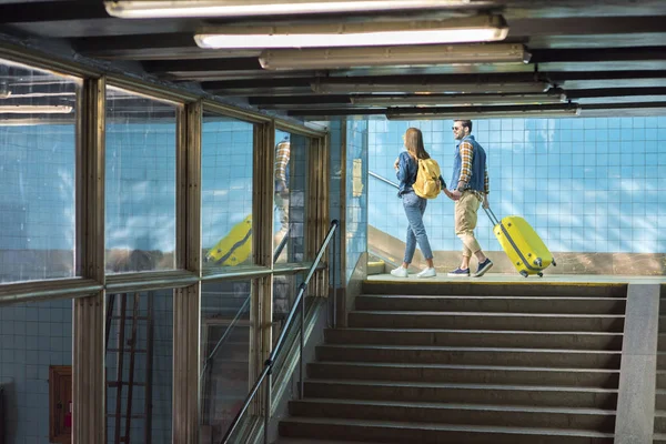 Stylish couple with backpack and wheeled bag going upstairs at subway — Stock Photo