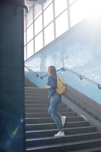 Vue arrière du touriste féminin avec sac à dos allant à l'étage au métro — Photo de stock